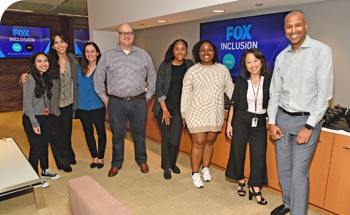 Eight diverse FOX employees standing in the FOX office