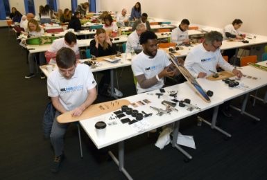 A group of FOX employees sitting at tables putting together skateboards.